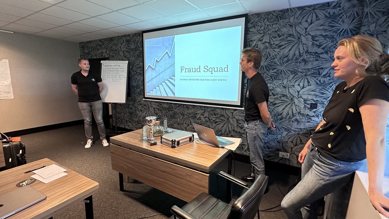 Three students stand beside their title slide reading Fraud Squad.