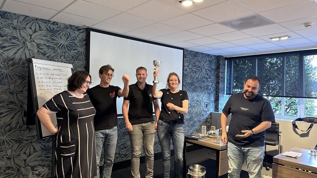 A team member raises the trophy while the rest of the group applauds.