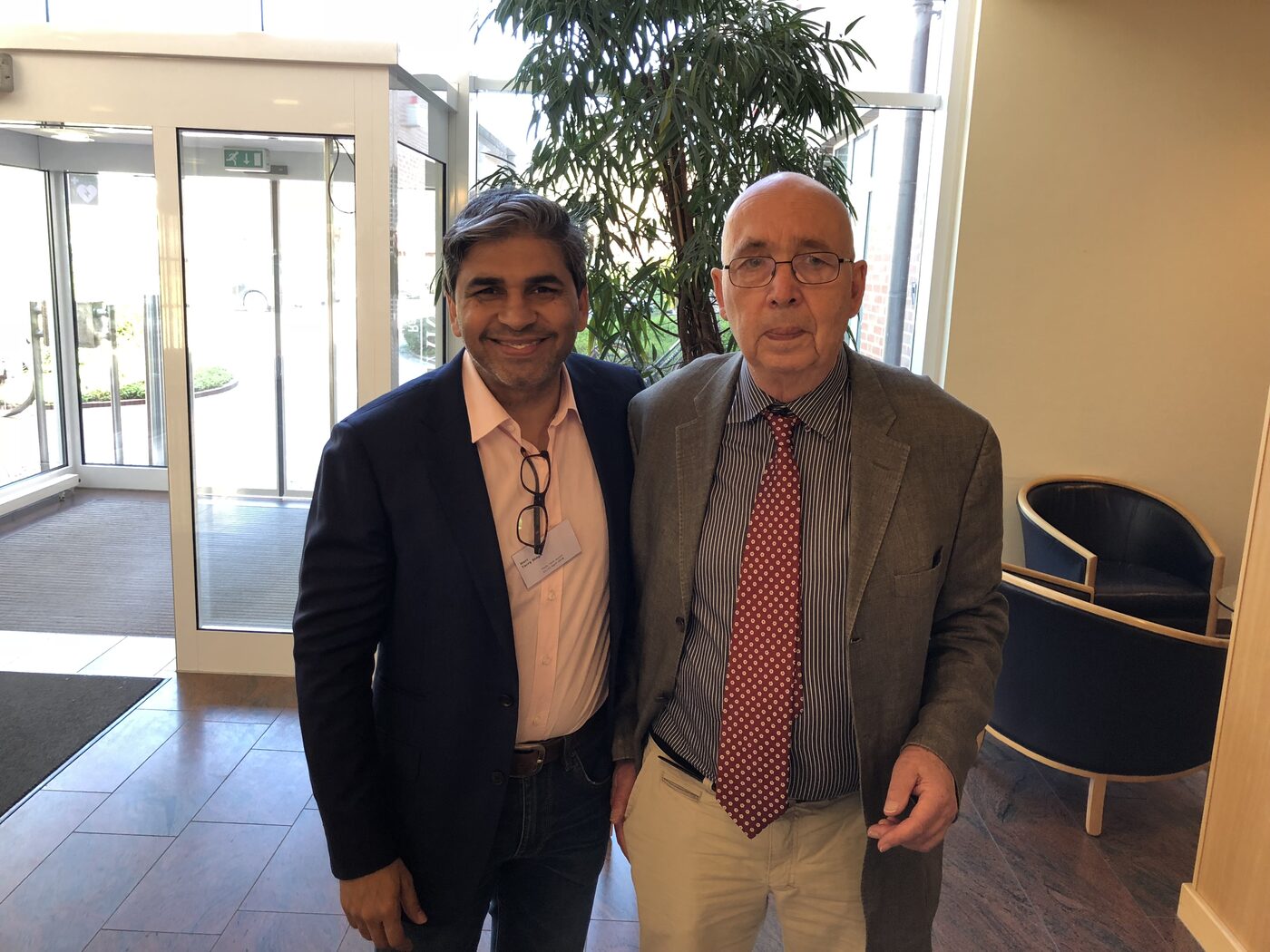 Tarry Singh, wearing a delegate badge, stands with one of the meeting's hosts in the lobby of Seminarhotel Aurich.
