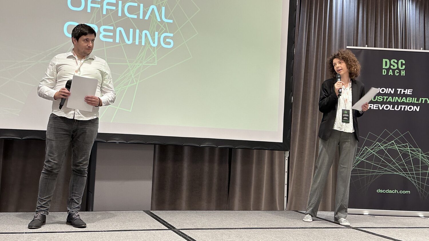 Two hosts on stage under a slide reading Official Opening, a DSC DACH banner beside them reading Join the AI sustainability revolution.