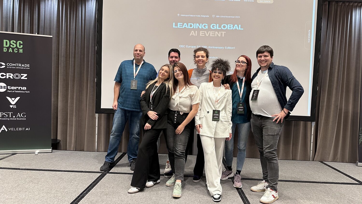 Eight members of the organising team stand together on stage in front of a screen reading Leading Global AI Event, DSC Europe 24 tenth anniversary edition.