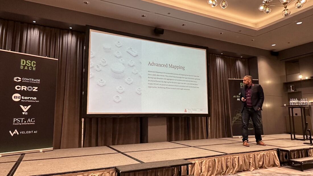 A speaker crosses the stage in front of a slide headed Advanced Mapping, the DSC DACH sponsor banner to his left.