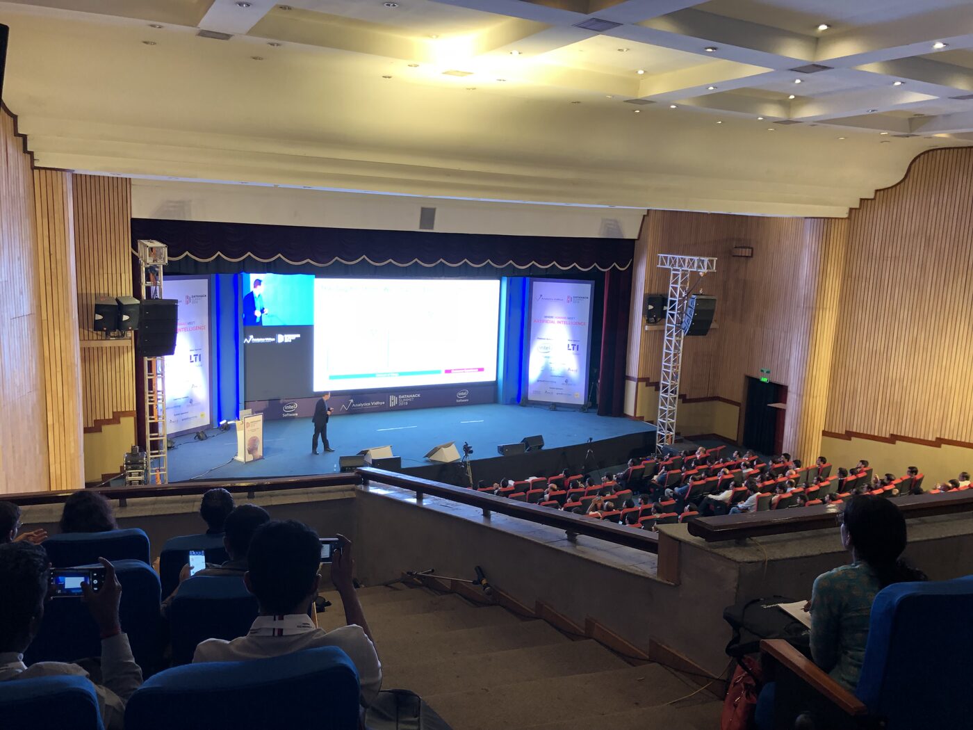 The DataHack Summit main auditorium from the floor, the stage lit and rows of delegates seated across the hall.