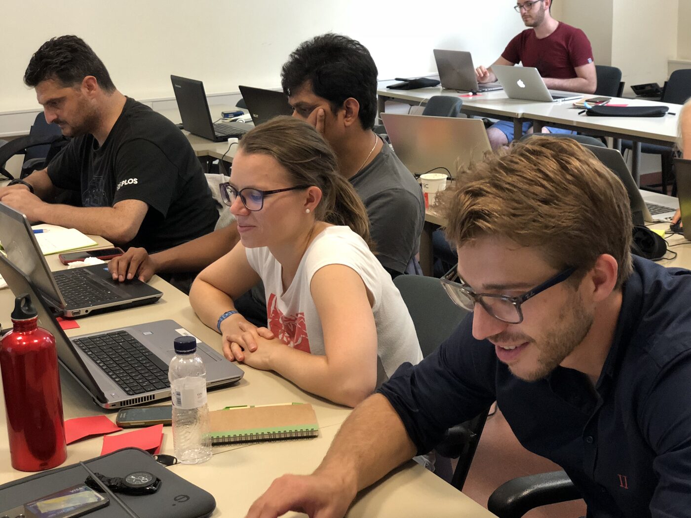 Four participants working through a coding exercise side by side at laptops.