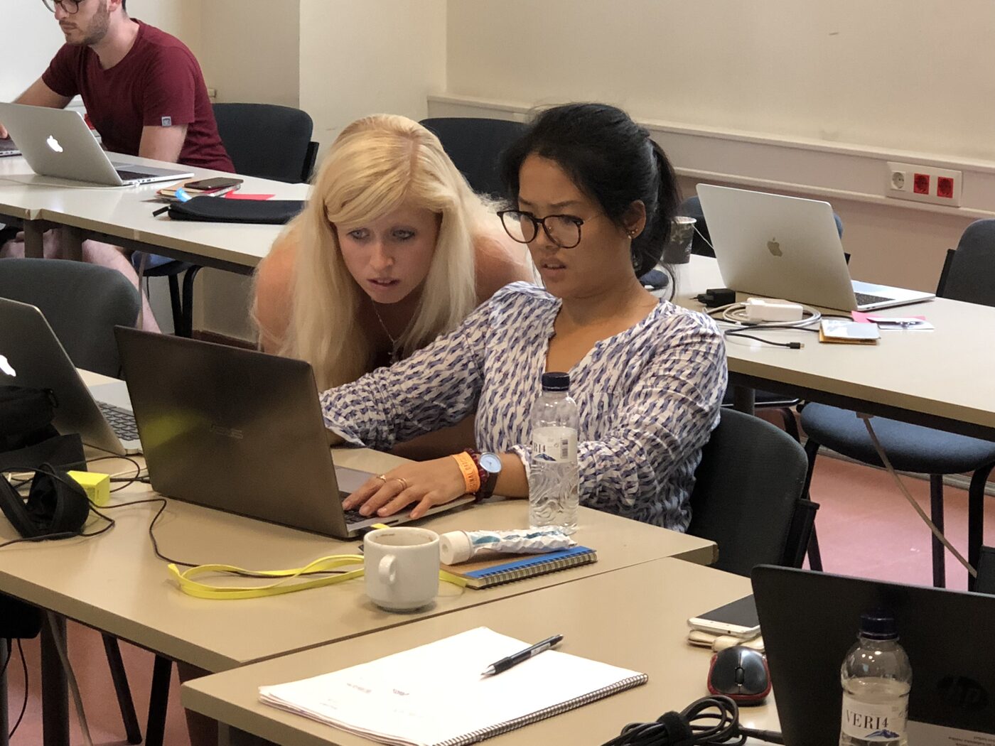 Two participants leaning over one laptop together, working through the notebook exercise.