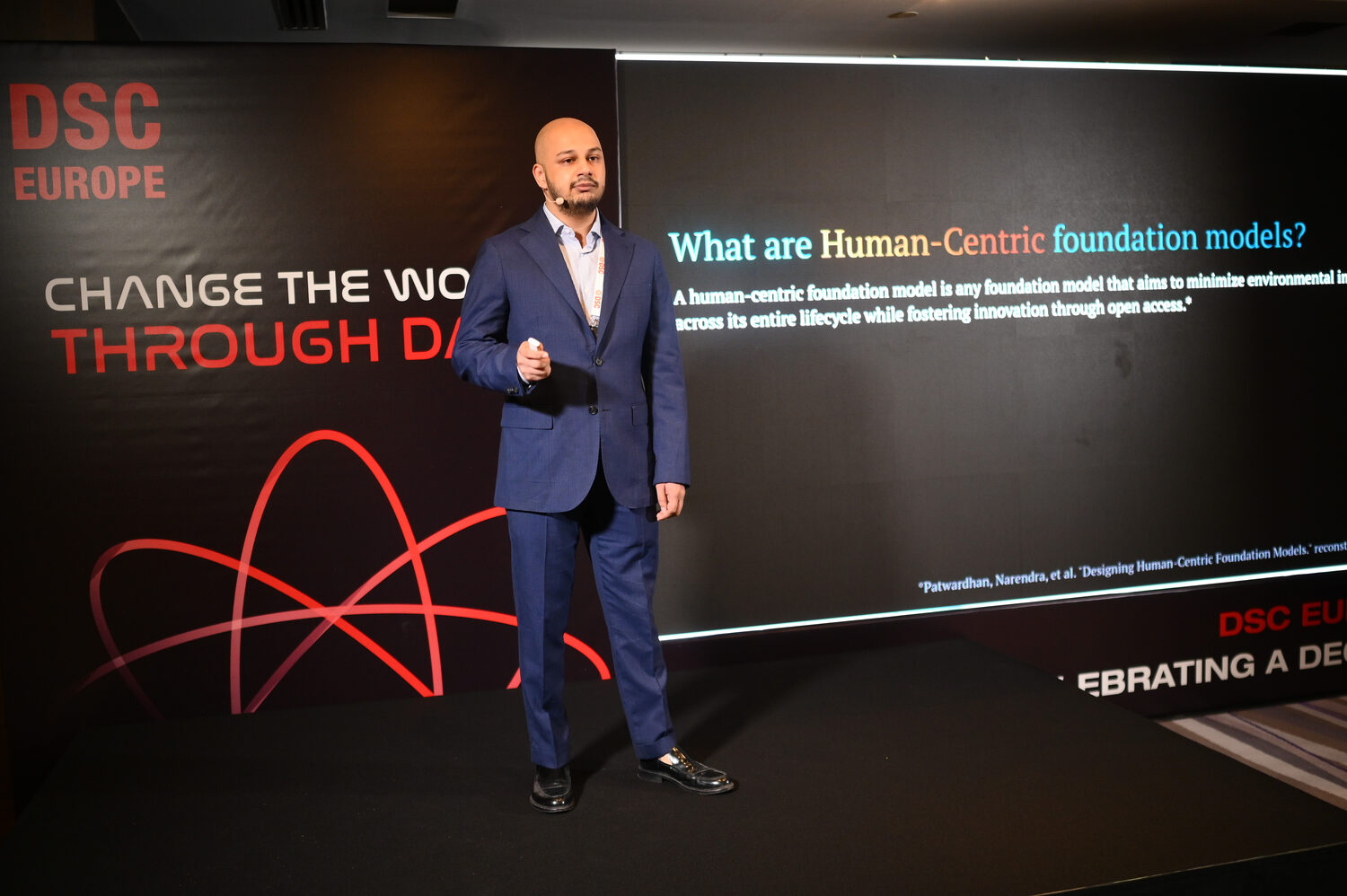 A speaker in a blue suit on the DSC Europe main stage beside a slide reading What are Human-Centric foundation models?, cited to Patwardhan, Narendra, et al.