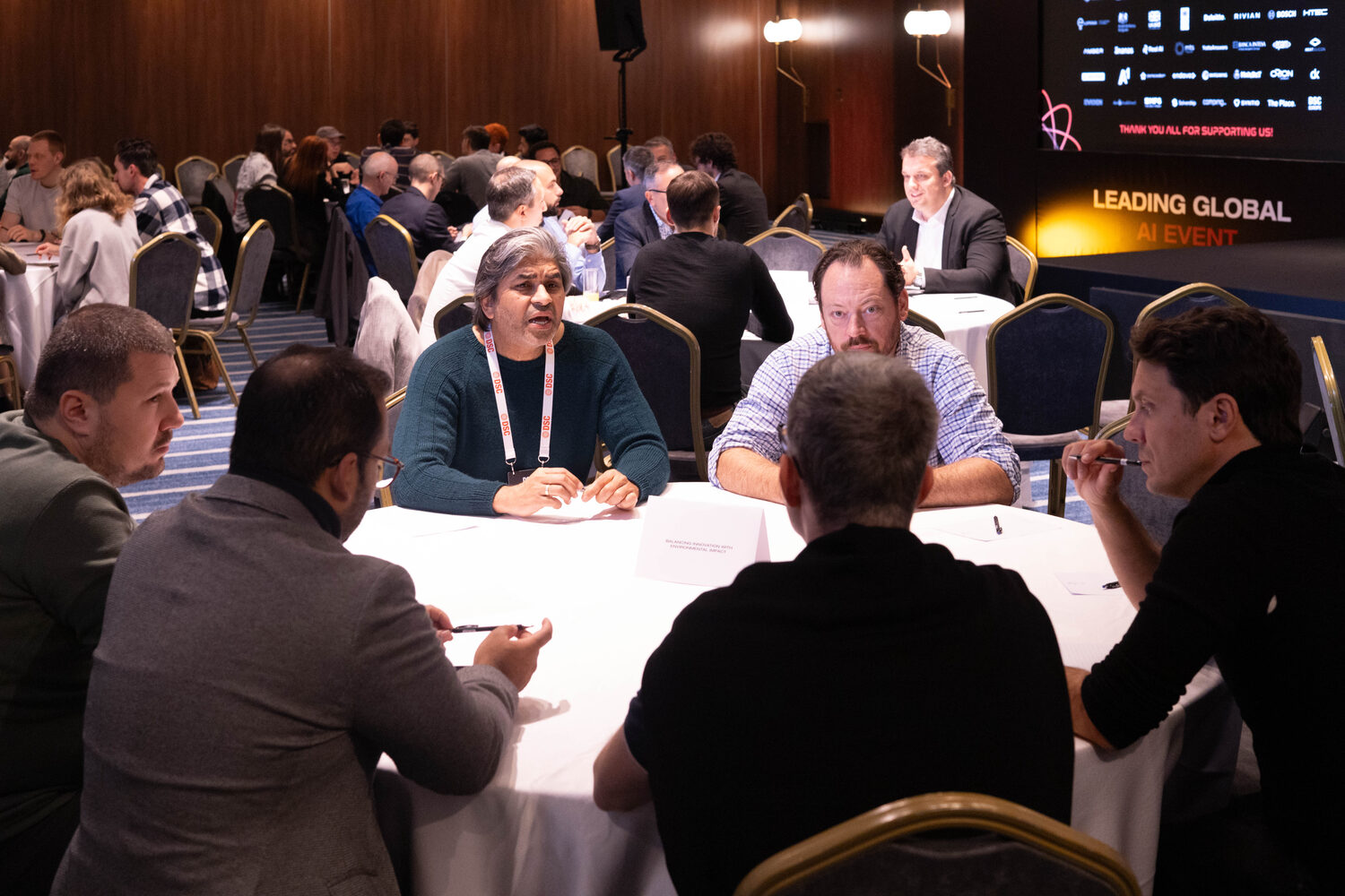 Delegates working around round tables at an evening session