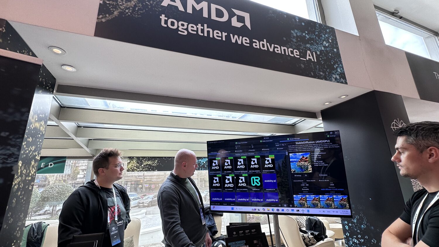 AMD expo stand under a banner reading together we advance_AI, three people at a screen showing Stable Diffusion model tiles.