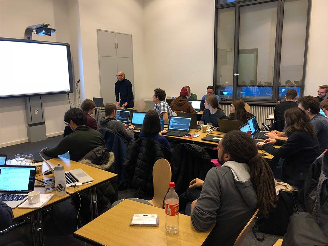 The full workshop floor, participants working on laptops