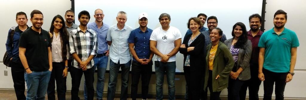 The full Chicago cohort, around sixteen people, standing shoulder to shoulder in front of the lecture room's projection screen at the end of the sessions.