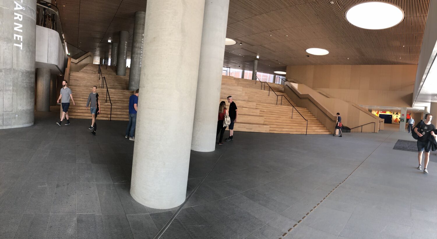 The Vandrehallen at Mærsk Tårnet, University of Copenhagen, with signage to the auditoriums and teaching rooms above the wooden stair.