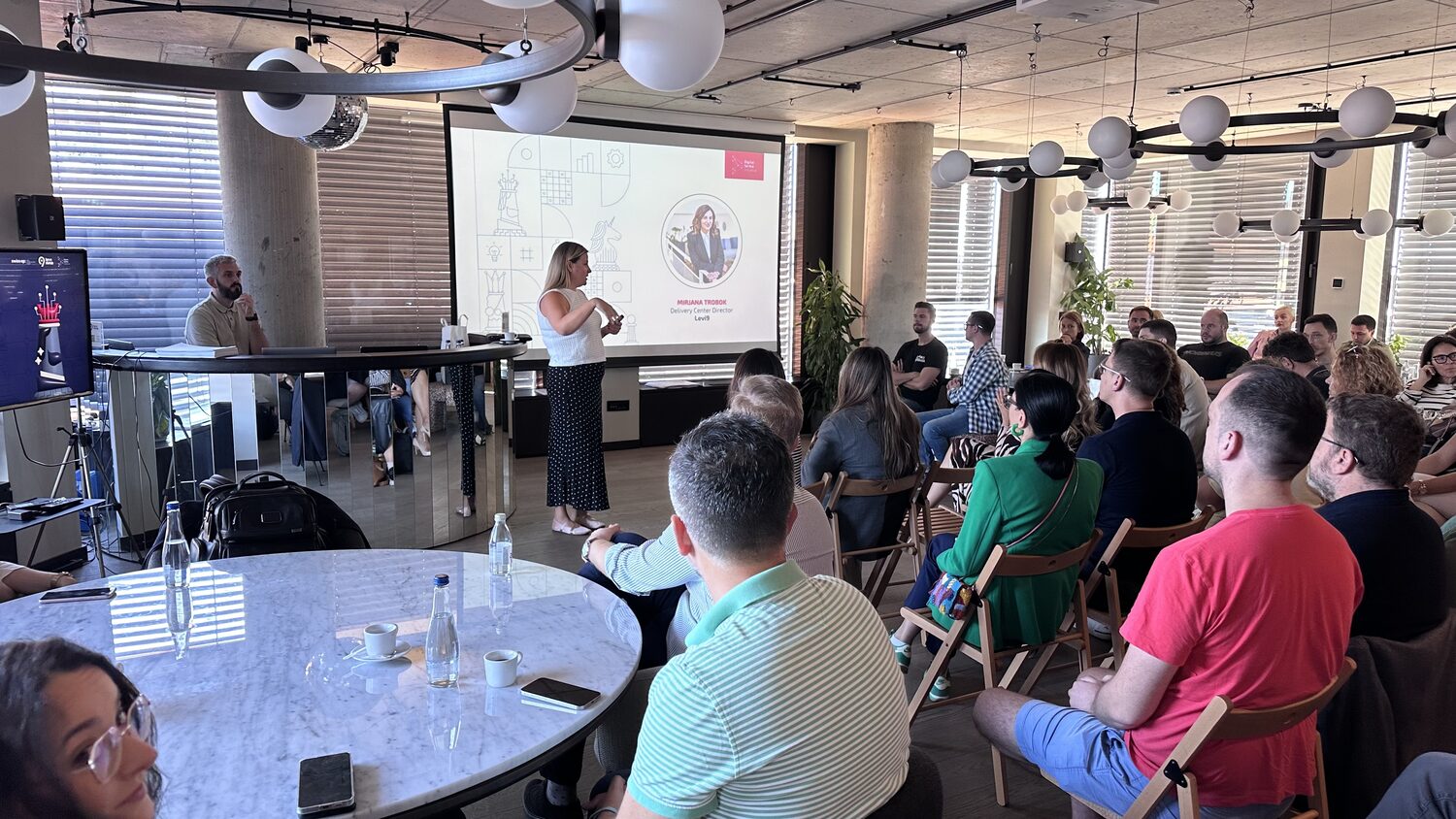 Mirjana Trobok presents to a full room at Levi9 in Novi Beograd, her name and title on the screen behind her, audience seated in folding chairs and armchairs.