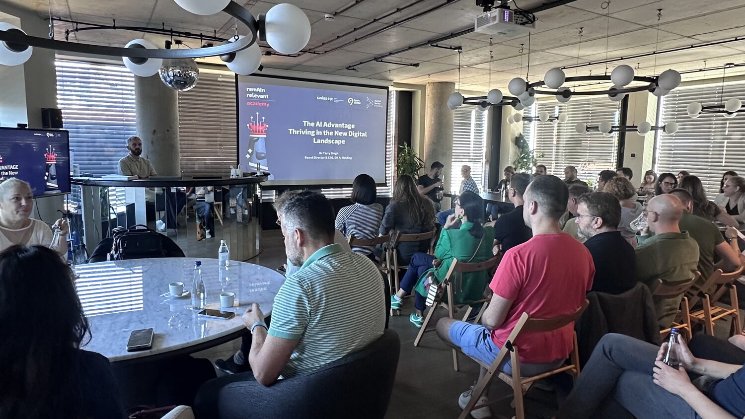 Seated audience facing a projection screen reading The AI Advantage, with Swiss EP, Levi9 and Digital Serbia Initiative logos along the top of the slide.