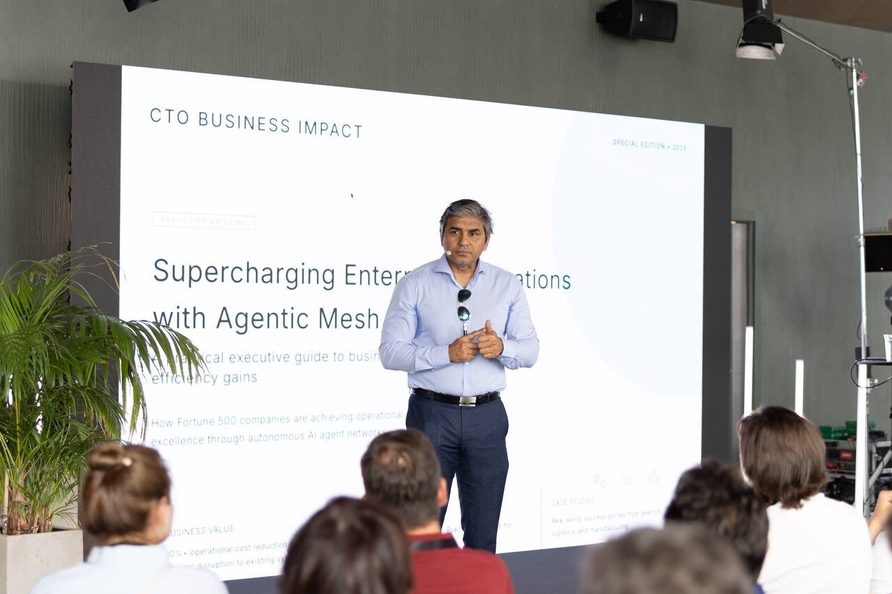 Delivering the agentic mesh keynote, the CTO Business Impact title slide on the screen behind and the room seated in front.