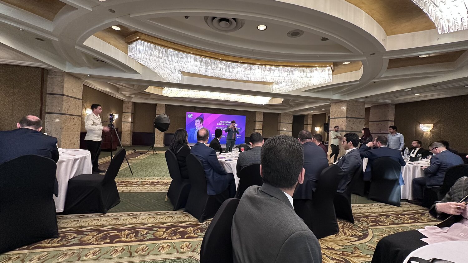 The DSC MENA ballroom in Cairo seen from the back, round tables and a seated audience facing the stage.