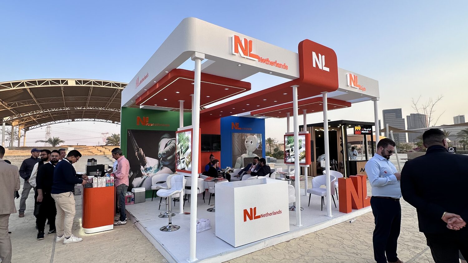 The NL Netherlands pavilion at the New Administrative Capital site in the late afternoon, delegates at the coffee counter.