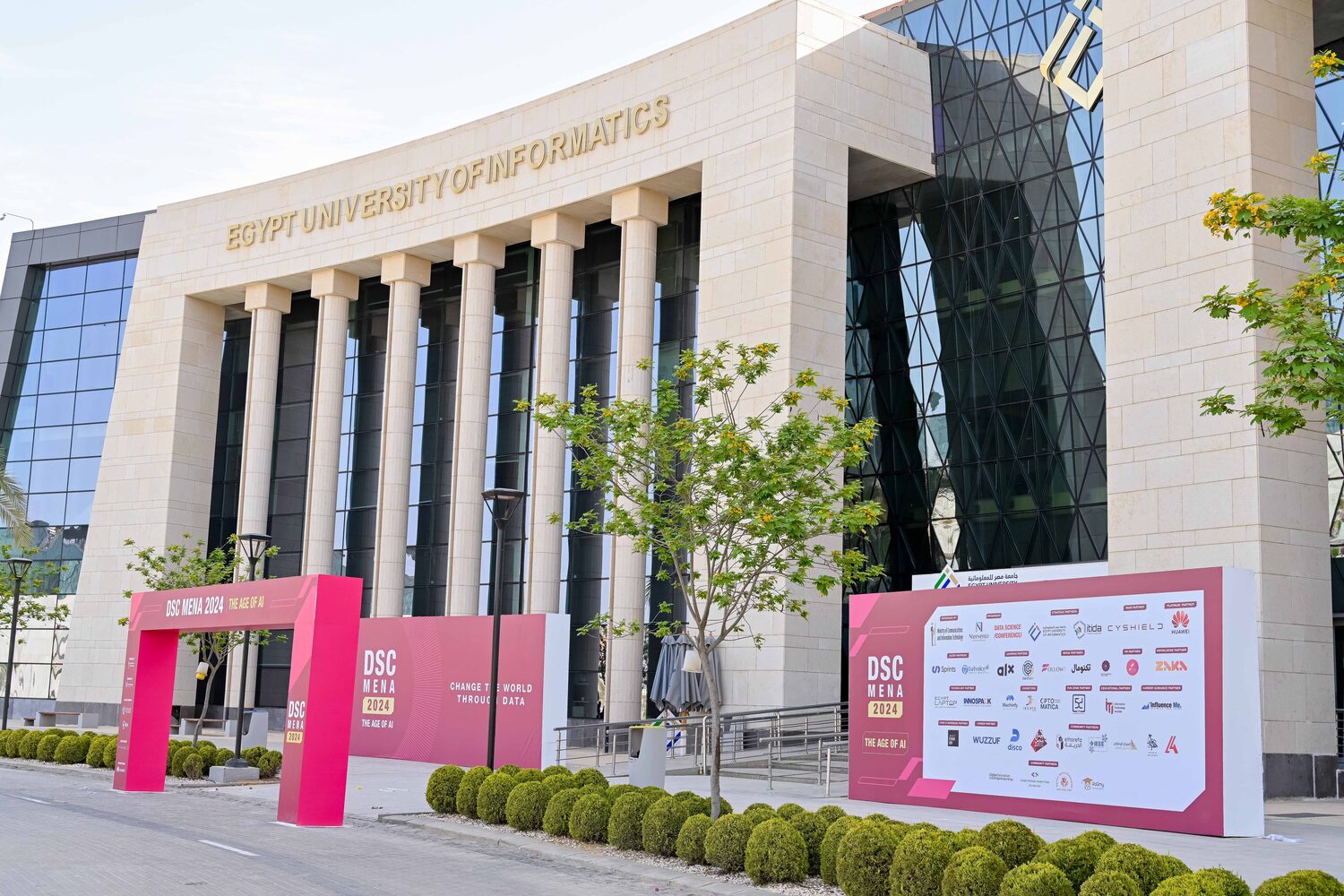 Egypt University of Informatics with DSC MENA 2024 arches, a Change the World Through Data hoarding and the partner wall on the forecourt.