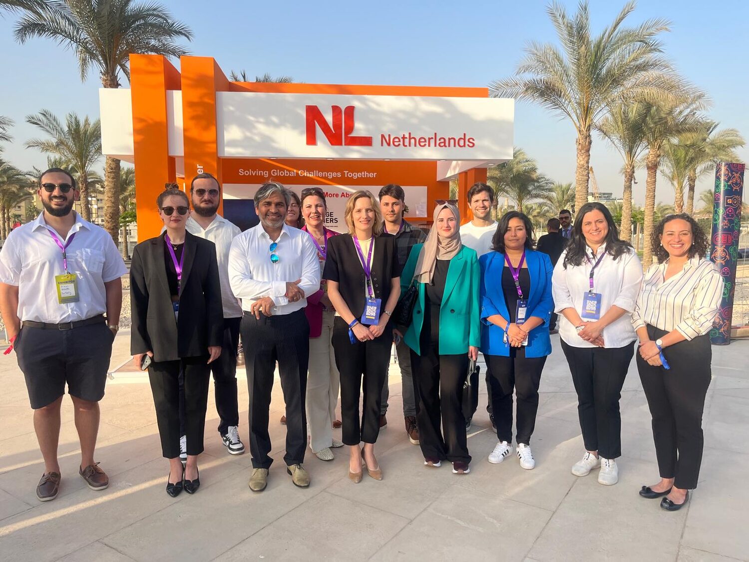 The Netherlands delegation lined up in front of the orange NL pavilion at the Grand Egyptian Museum, palms behind them, lanyards on