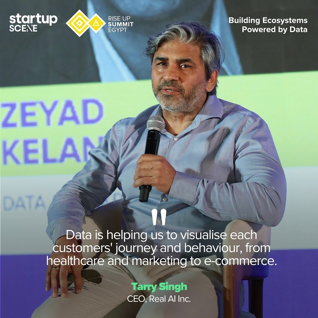 Tarry Singh speaking into a handheld microphone from a panel chair, captioned CEO, Real AI Inc.