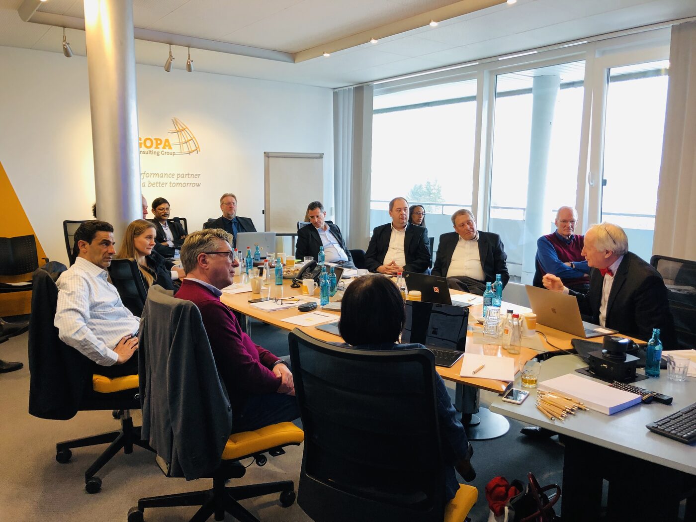 The full room in discussion, daylight coming through the window wall, a GOPA roll-up banner at the back of the room.
