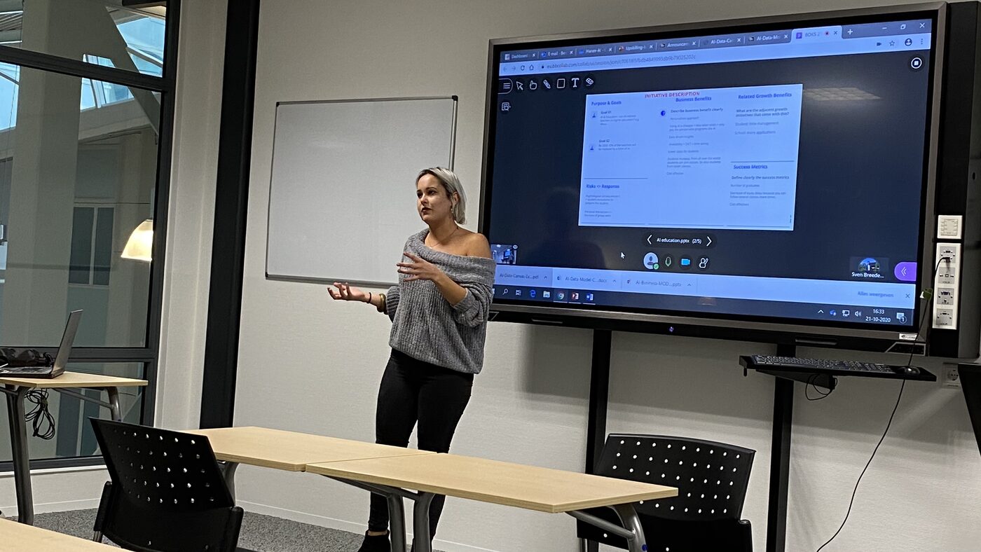 A student presents a five-slide deck on AI in education, the initiative description canvas filled in behind her. Taskbar reads 16:33.