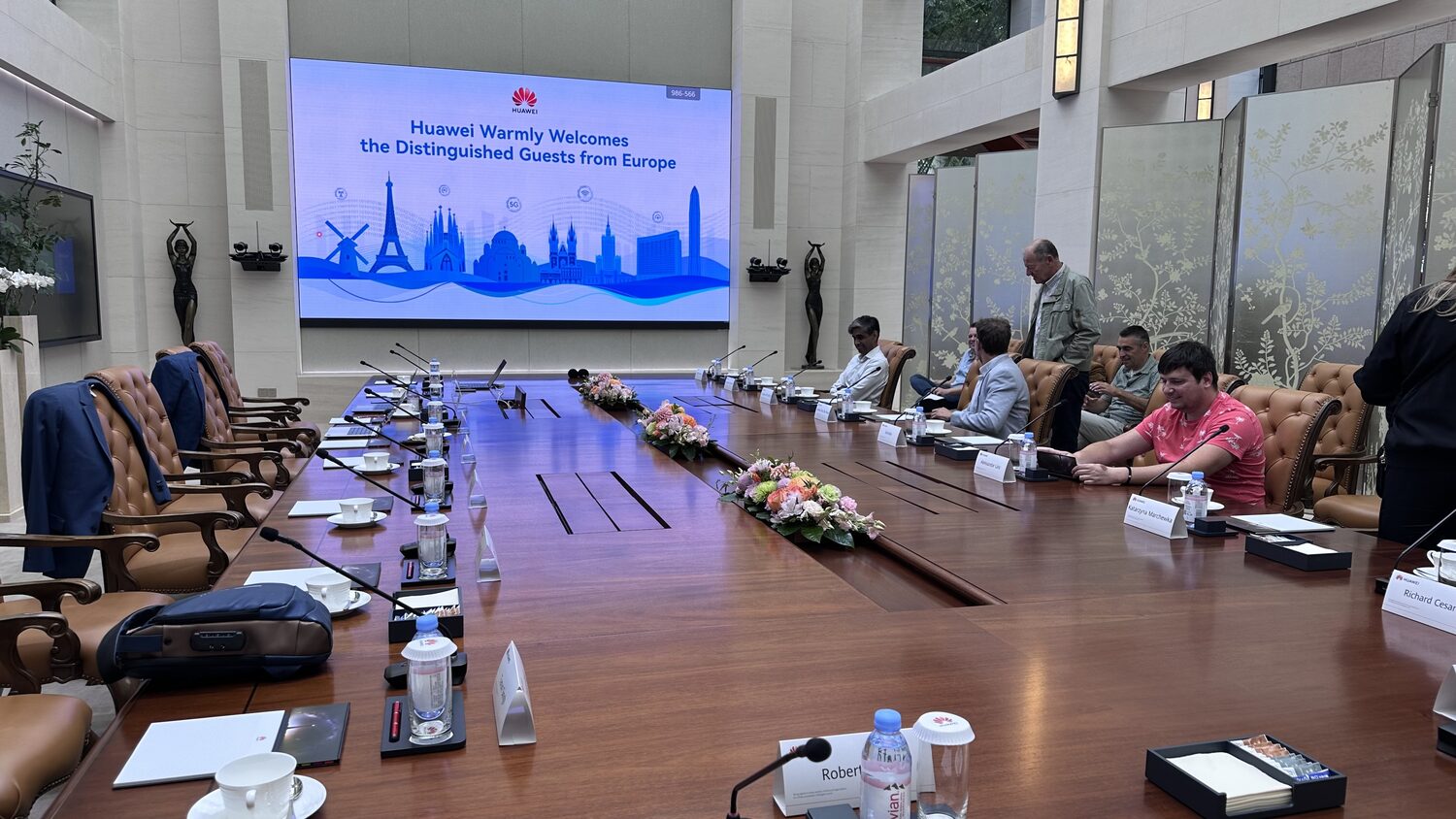 Huawei boardroom on the second morning, 1 July, the welcome screen lit and the table set with microphones and name cards.