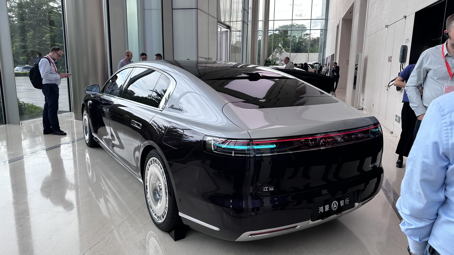 A Maextro S800 saloon on display in a Huawei showroom lobby in Shenzhen, delegates with lanyards standing around it, 30 June.