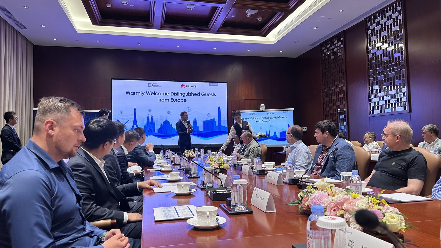 Delegates and Huawei staff along the boardroom table, Bantian, 30 June, flowers and place cards between them.