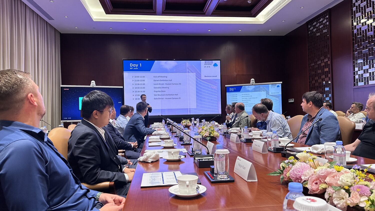 The Day 1 agenda projected on the boardroom screen, delegates seated either side, Shenzhen, 30 June.