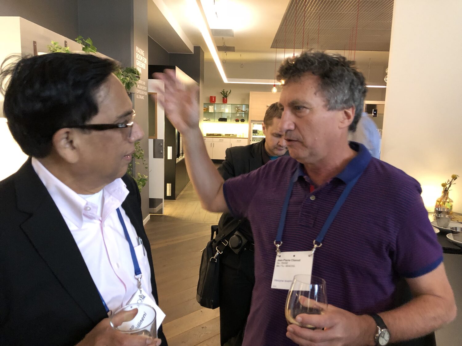 Two delegates in conversation at the conference reception, ICSE lanyards and badges visible.
