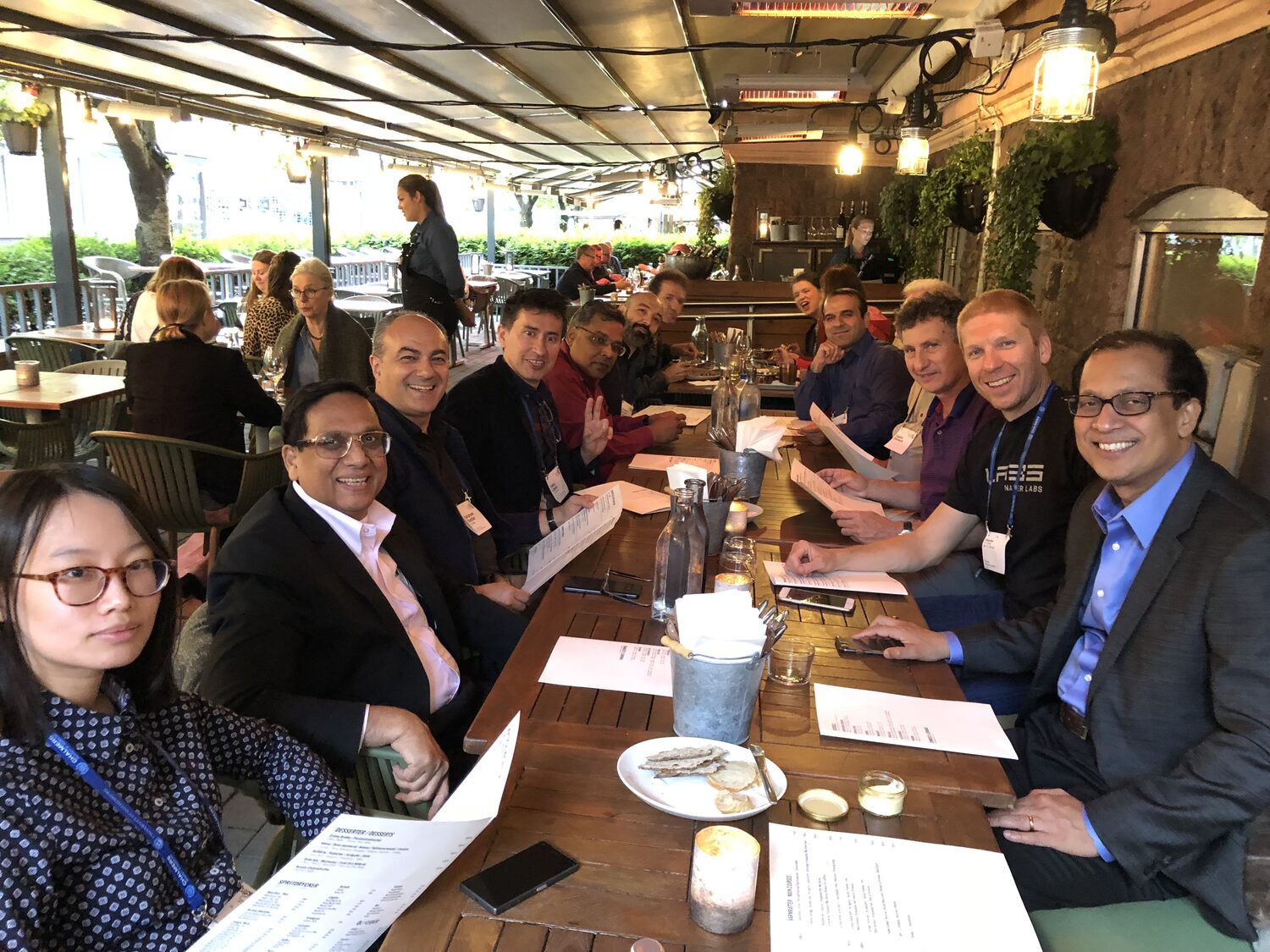 A long table of ICSE delegates on a terrace in Gothenburg, lanyards still on.