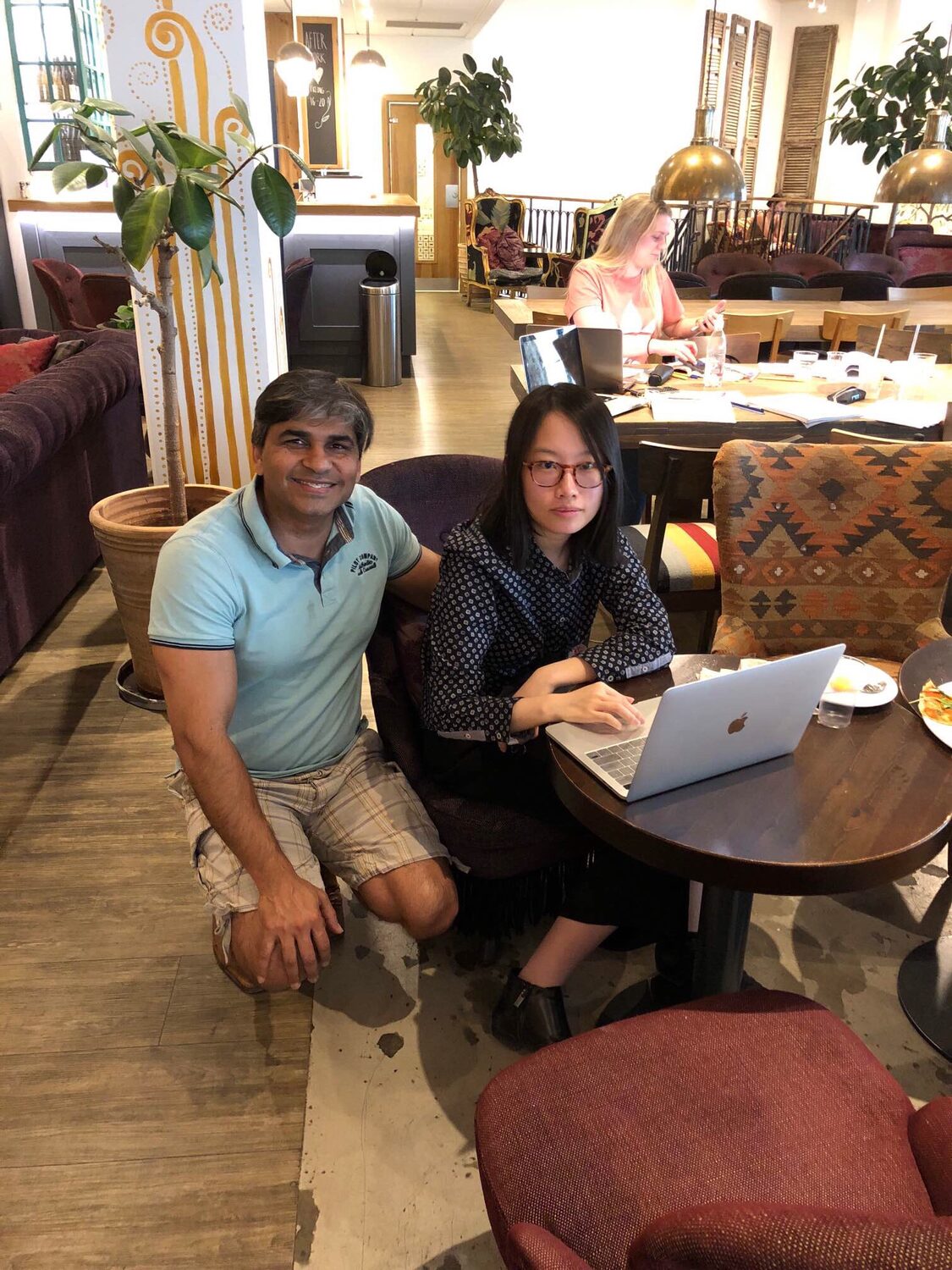 Tarry Singh and a research collaborator working at a laptop in the venue lounge, other delegates at tables behind.