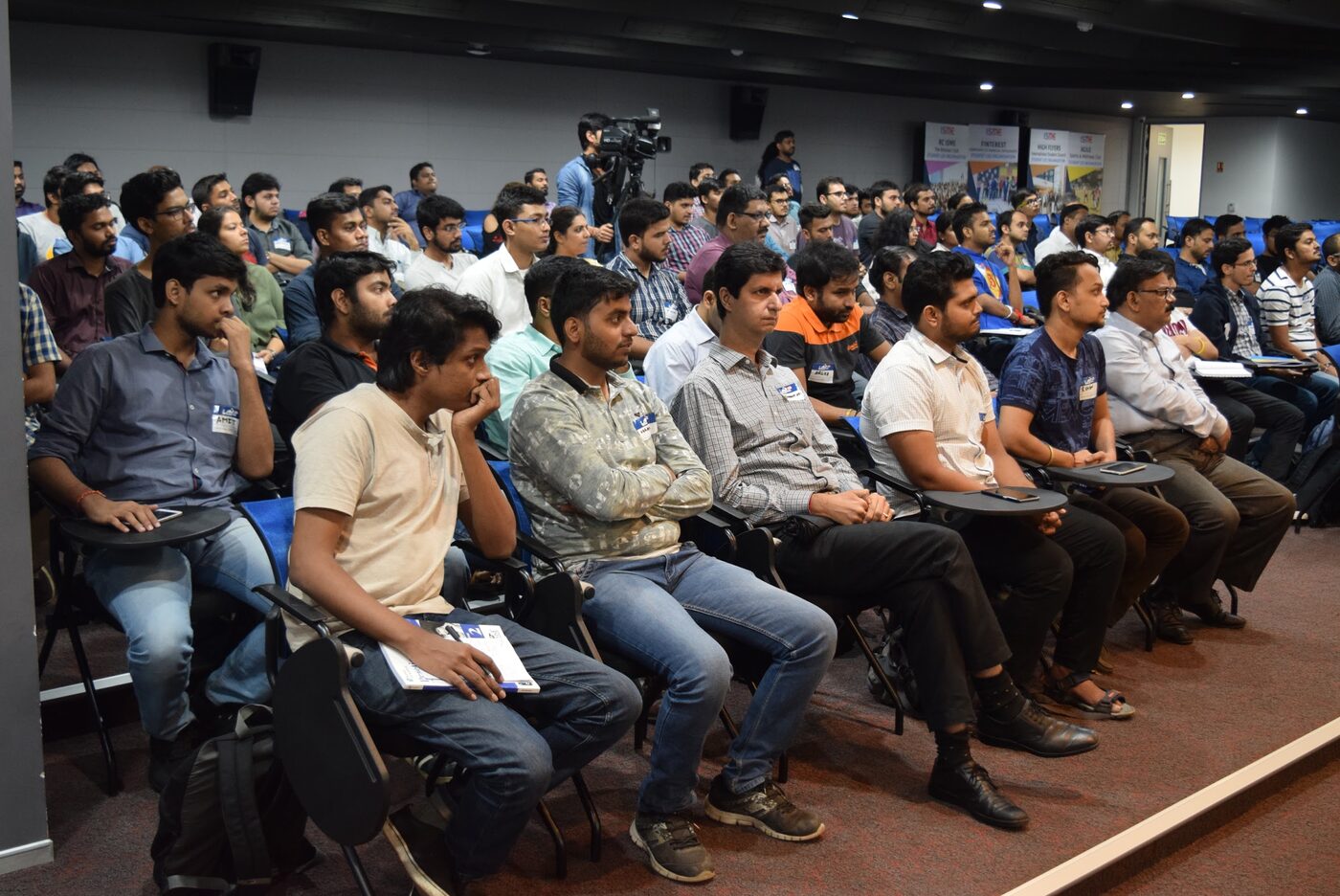 A full seated audience at the DataGiri lecture in Mumbai, rows of attendees facing the stage with a video camera set up at the back of the room.