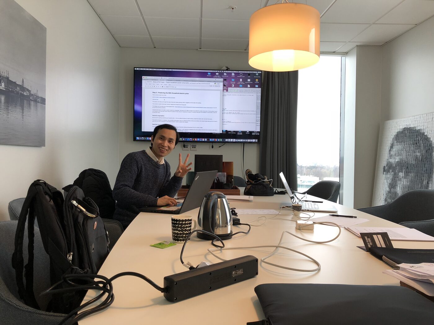The team's Helsinki workroom on 25 February 2018. A laptop is open at the table and the wall screen carries a Jupyter notebook headed "Nokia LSTM Project: Predict Household's power consumption" beside a terminal.