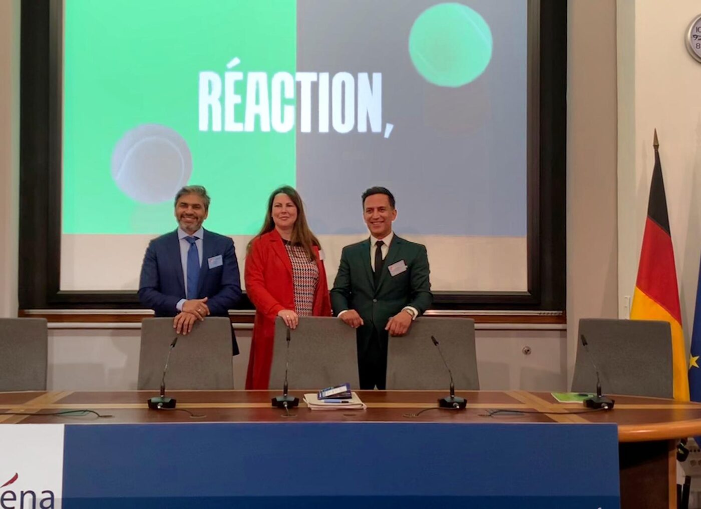 Three participants standing at the ENA panel table in front of a slide reading Réaction, with the ENA branding on the table front.