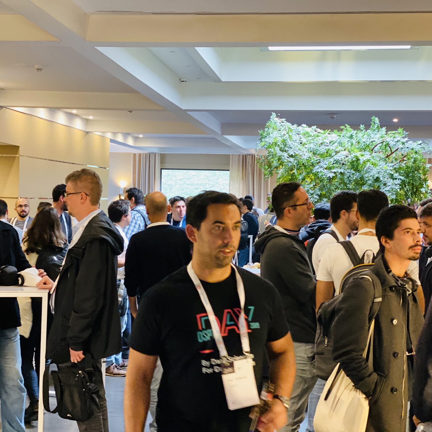 Attendees during a break at DSPT Day, several wearing lanyards and DSPT Day t-shirts, in the venue foyer.