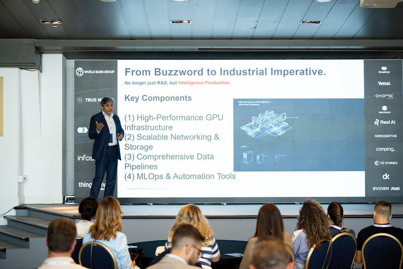 A full room of seated delegates watching a keynote slide headed From Buzzword to Industrial Imperative.