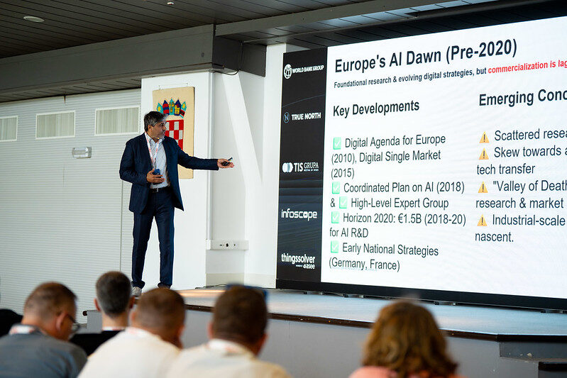 Tarry Singh pointing at a slide headed Europe's AI Dawn, Pre-2020, with the heads of the audience in the foreground.