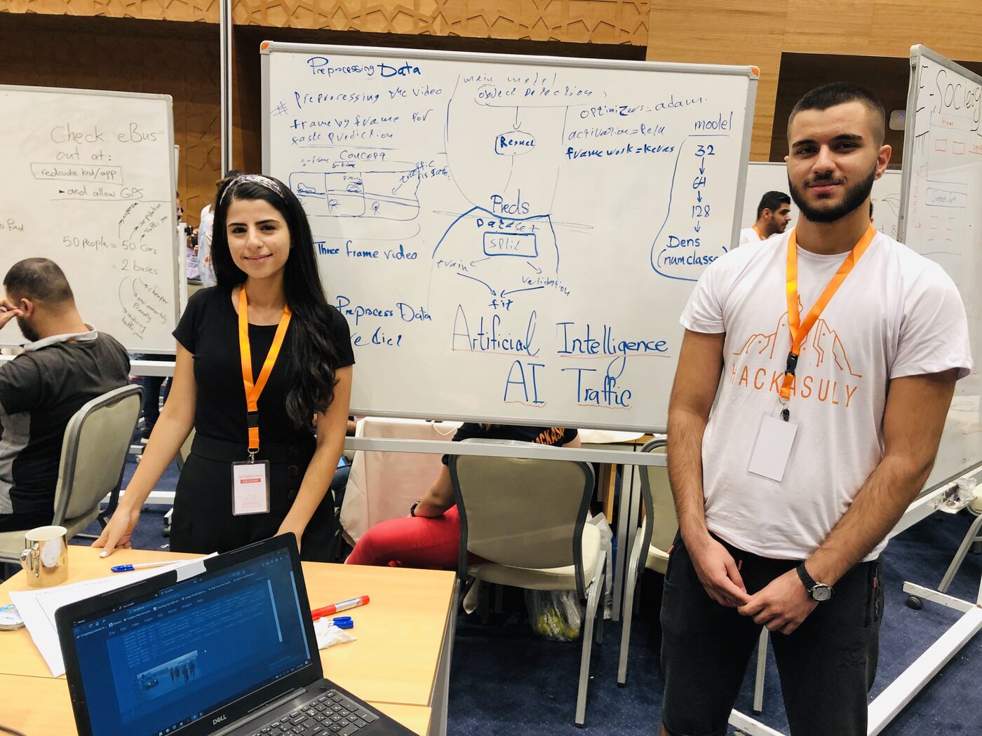 Two participants at a laptop beside a whiteboard headed Artificial Intelligence AI Traffic, showing three-frame video preprocessing into a ResNet with Keras and the Adam optimiser.