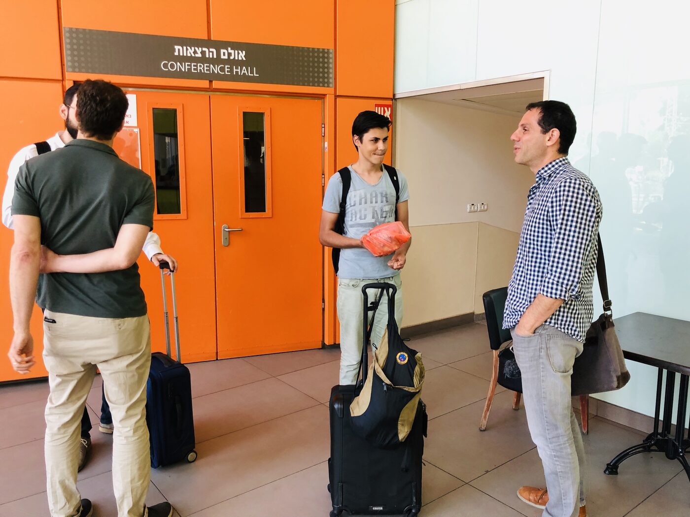Attendees talking in the foyer beside the bilingual Hebrew and English Conference Hall doors at the hospital.
