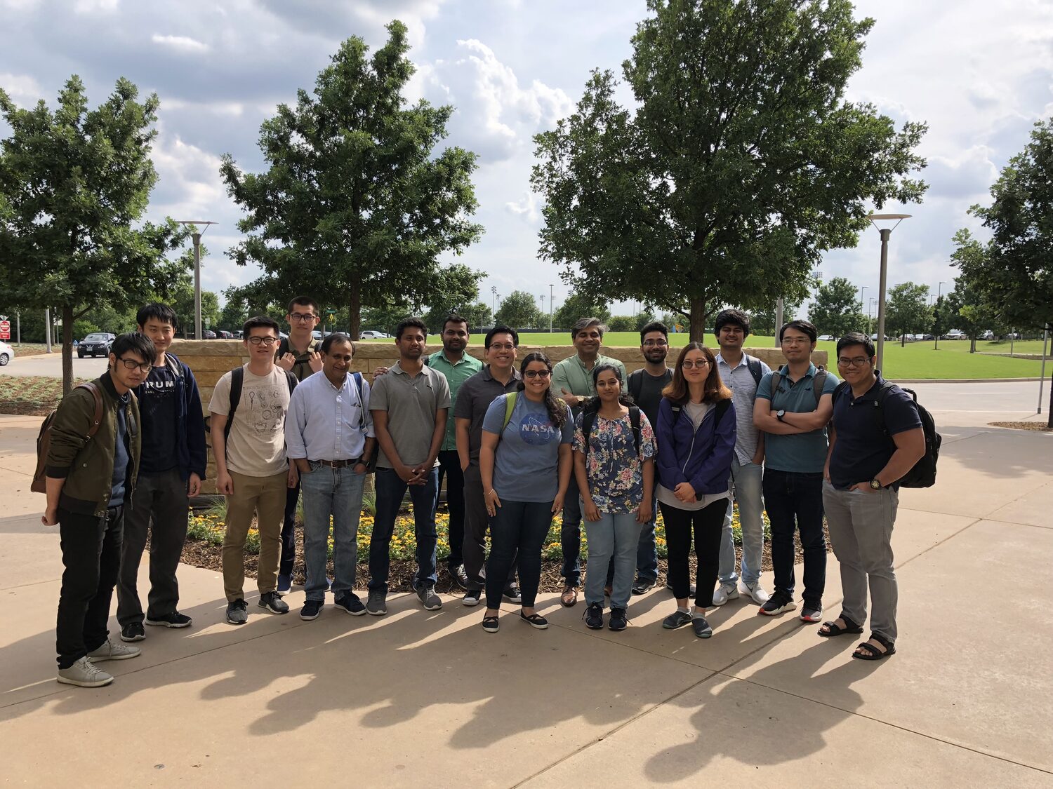 The workshop group standing together on a campus lawn under trees