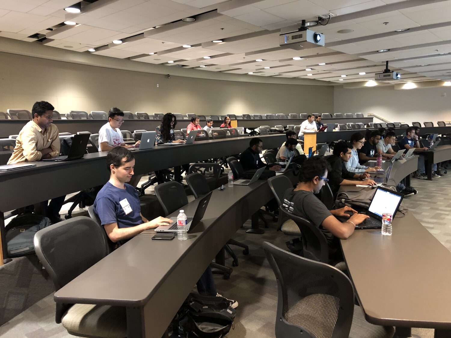 Delegates working on laptops along the curved desks of the lecture hall