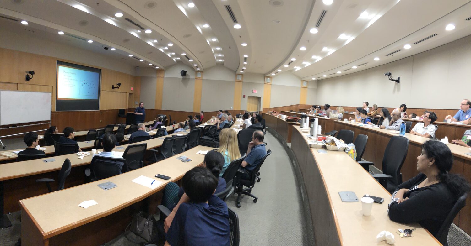 Panorama of the tiered lecture hall with delegates seated along the desks