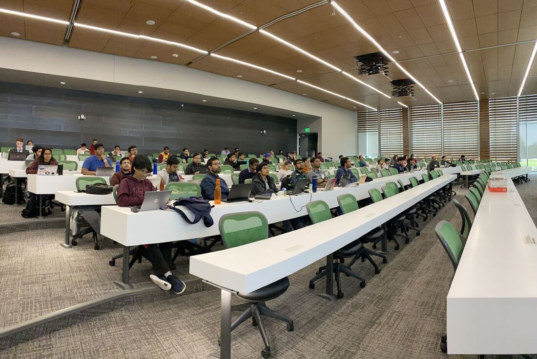 The lecture hall during a session, participants at the benches with laptops open.