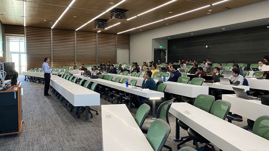 The lecture hall during a session, participants at the benches with laptops open.