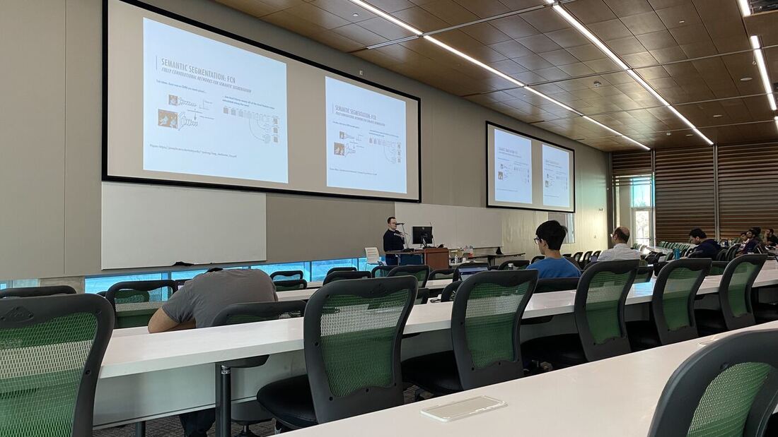The lecture hall during a session, participants at the benches with laptops open.