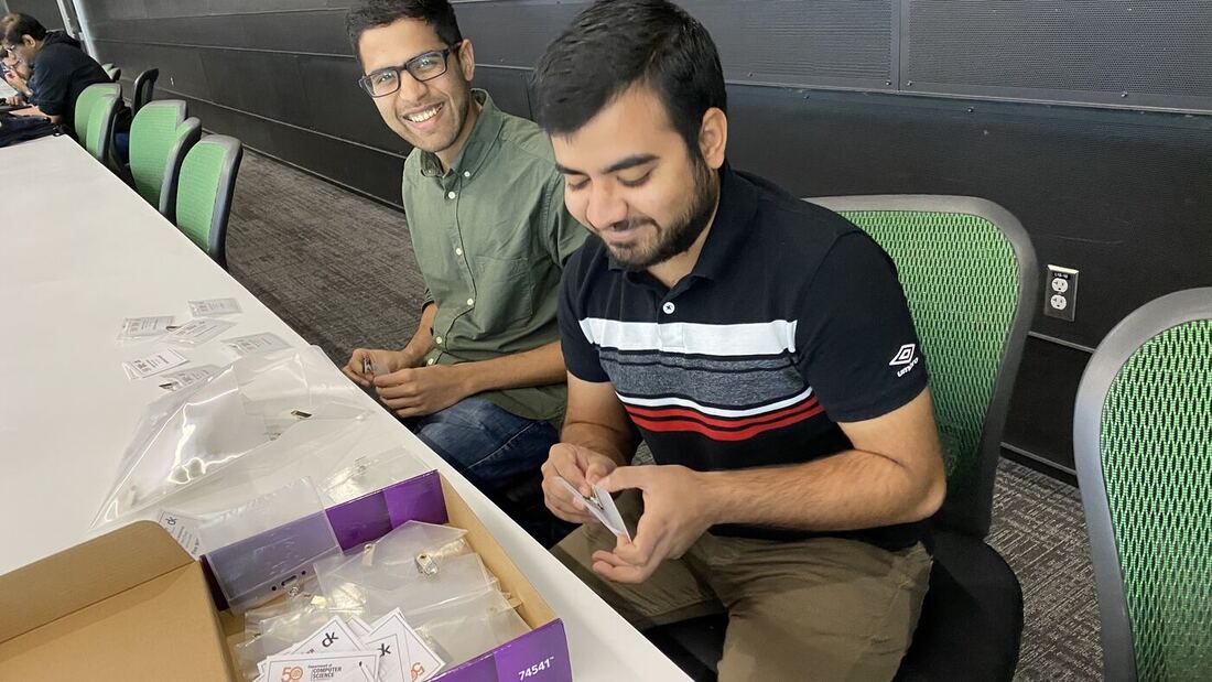 Two participants at a bench with the workshop kit open in front of them.