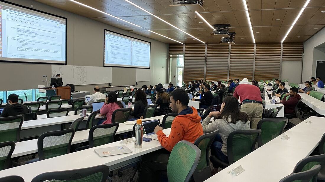 The lecture hall during a session, participants at the benches with laptops open.