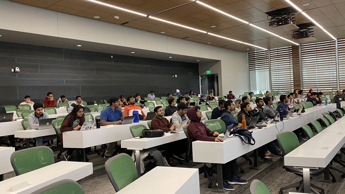 The lecture hall during a session, participants at the benches with laptops open.