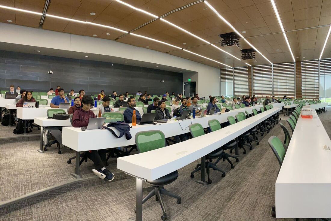 The lecture hall during a session, participants at the benches with laptops open.